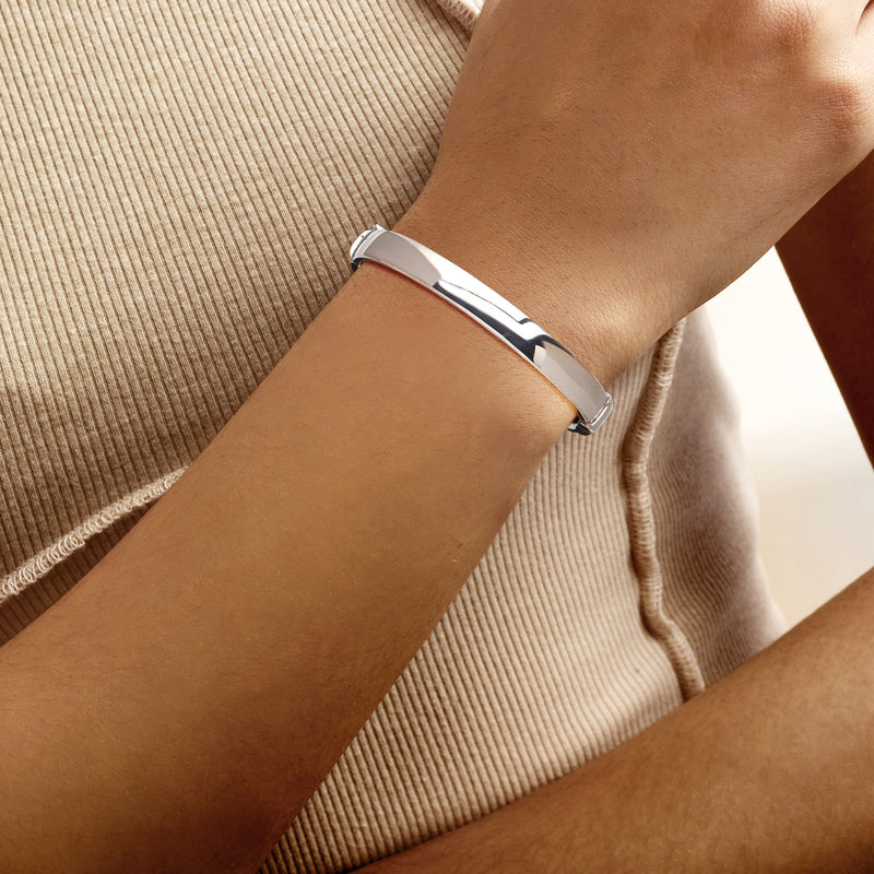 Sterling silver bangle on wrist, polished wide cuff with side clasp