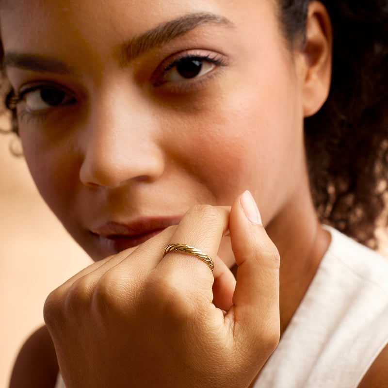 Twisted 14kt yellow gold band ring on finger
