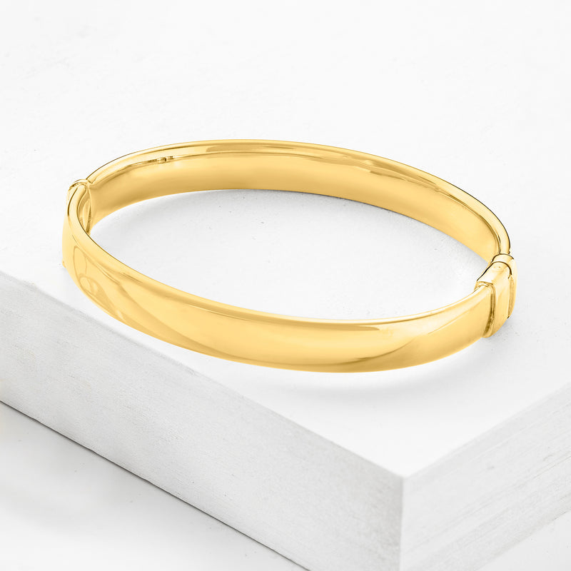 Gold-tone bangle bracelet with smooth oval band and small clasp detail