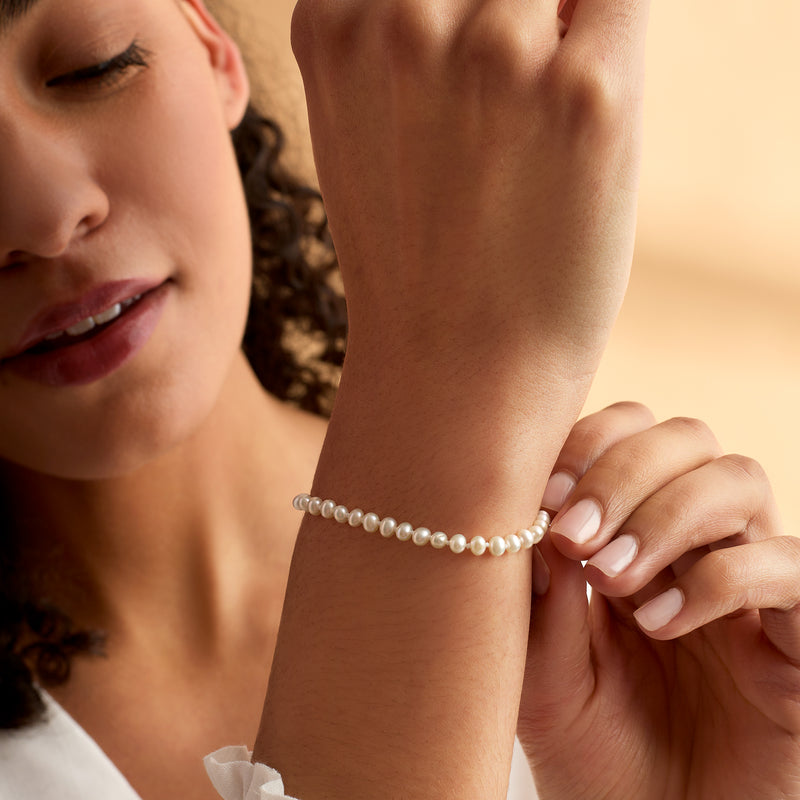 White pearl bracelet on wrist with small yellow gold clasp