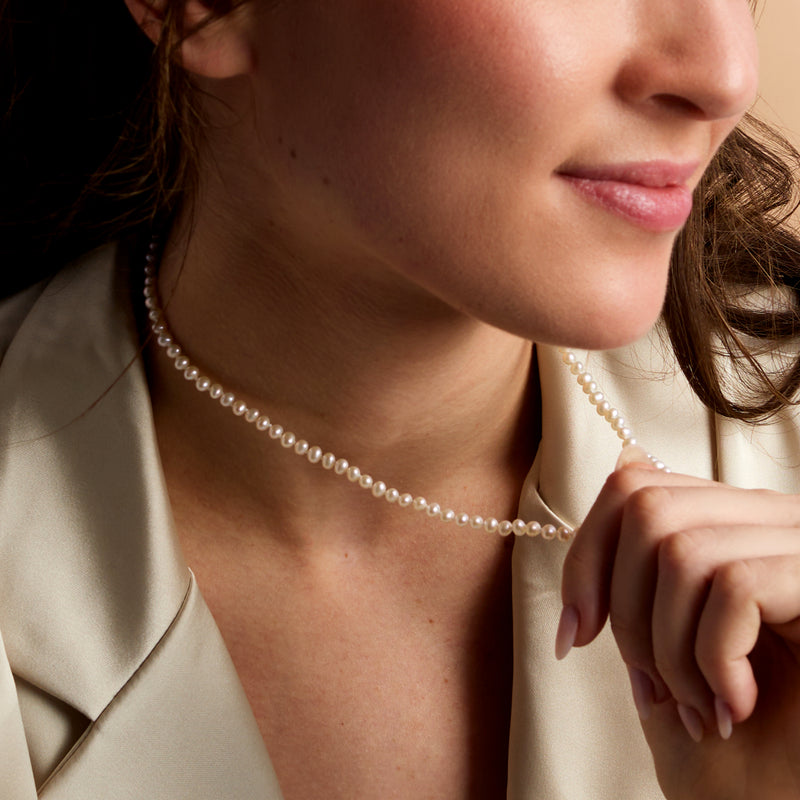 Cultured pearl necklace worn close-up, round white pearls with fine chain
