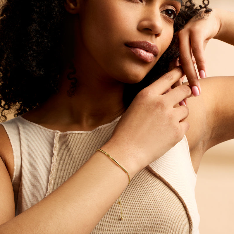 14kt yellow gold bolo bracelet worn on wrist with slim round bar and chain