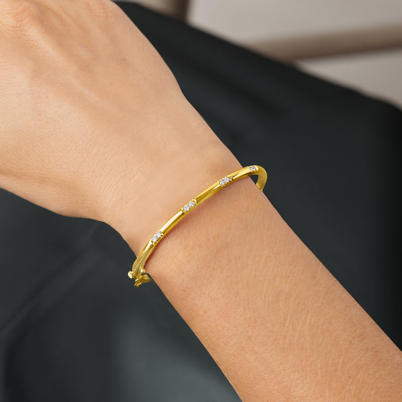 Gold bangle bracelet on wrist with small diamond stations and hinge clasp