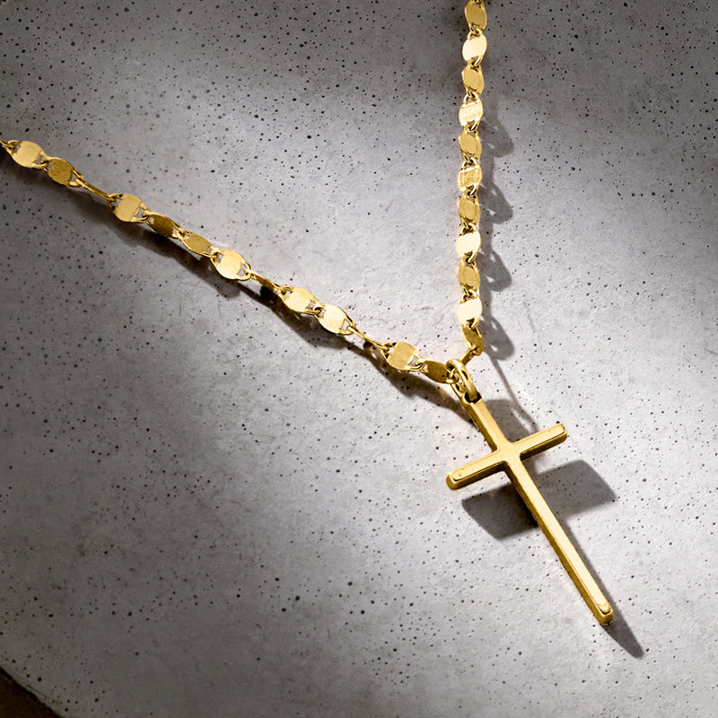 Gold cross pendant necklace close-up with long vertical cross and link chain