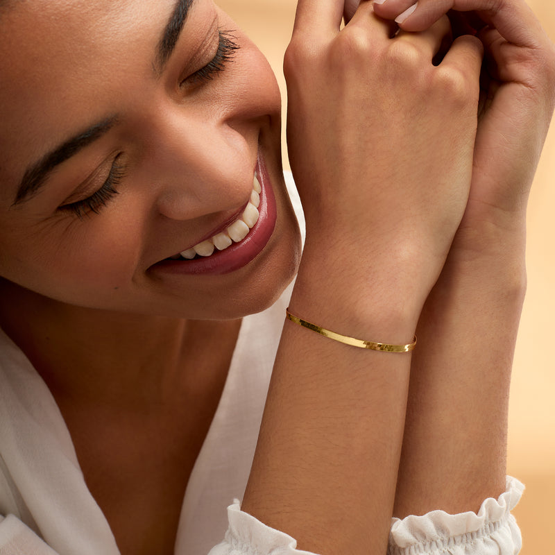Yellow gold herringbone bracelet worn on wrist with toggle clasp