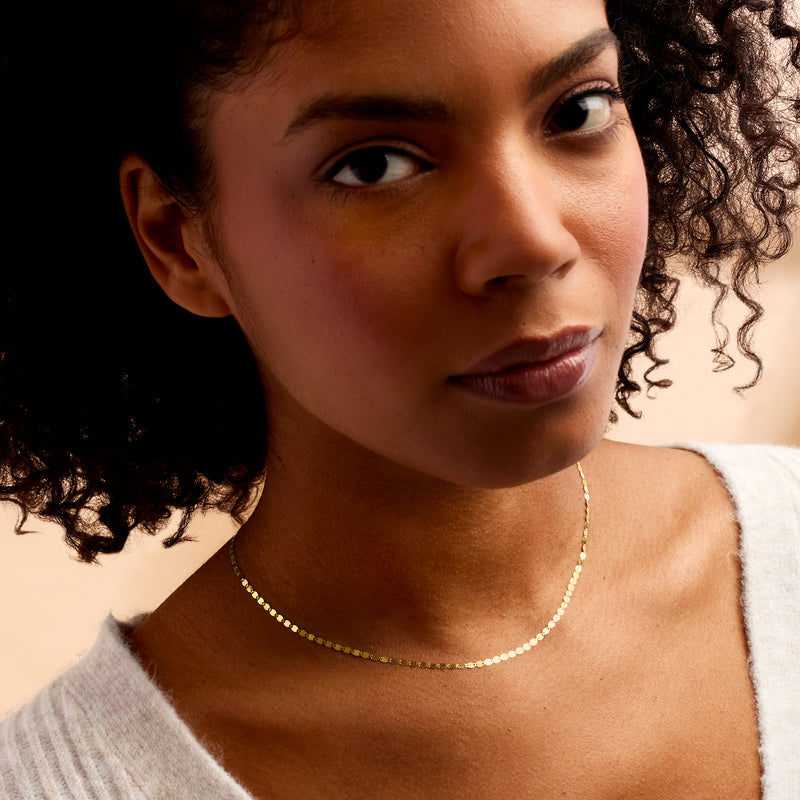 Yellow gold mirror-link necklace on model, delicate chain with small oval links