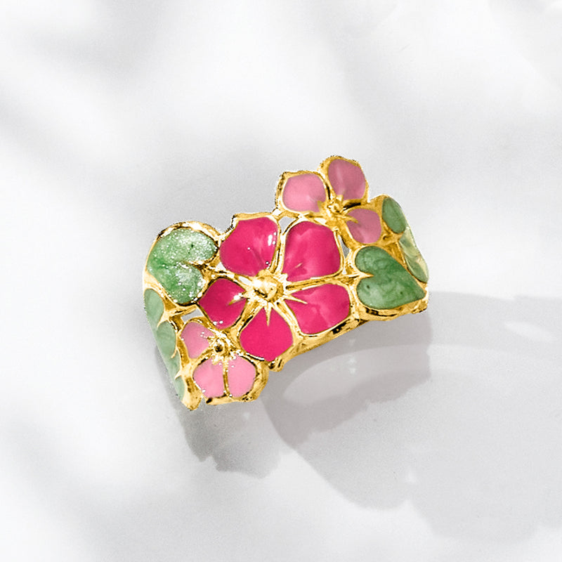 Gold enamel flower ring with pink center blooms and green leaf accents
