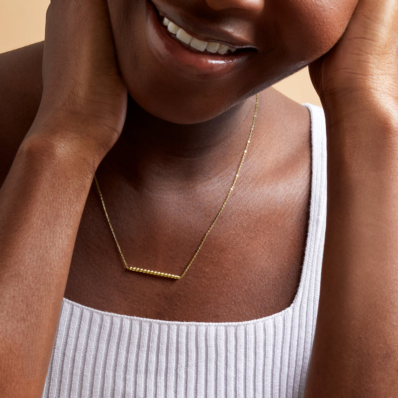 14k yellow gold twisted bar pendant necklace worn close to the neck