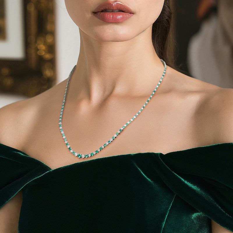 Sterling silver tennis necklace on model’s neck, green emerald stones with diamond highlights