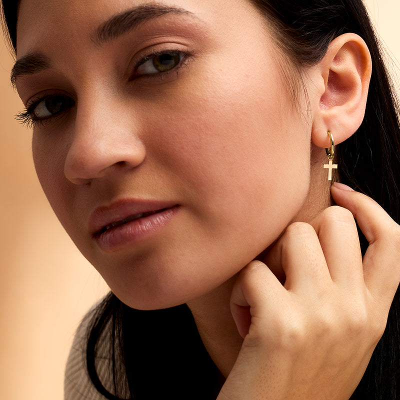 14kt yellow gold hoop earrings with small cross charm on ear
