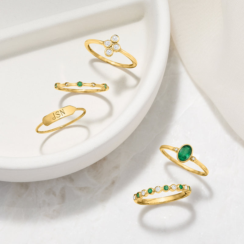 Gold stack ring with green emerald stones and tiny diamond accents on slim bands