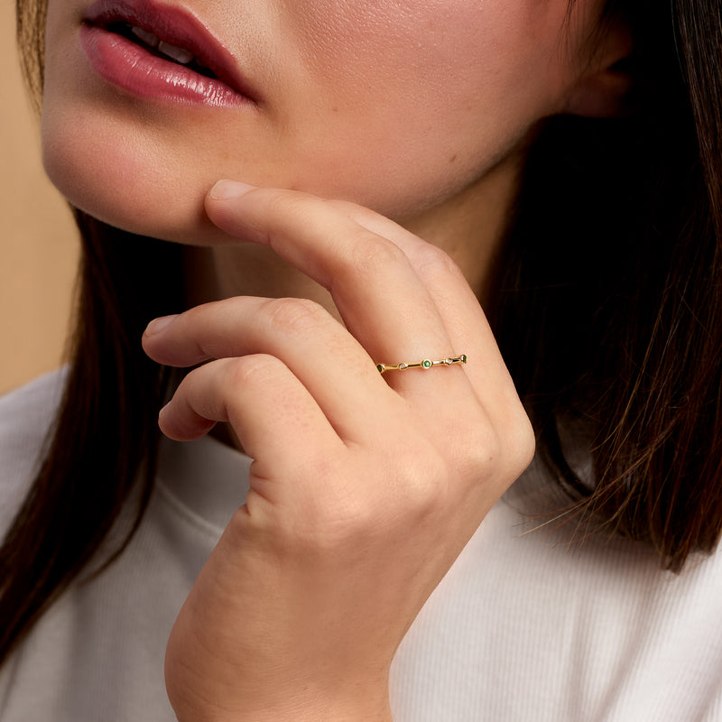 Emerald and diamond ring in 14kt yellow gold worn on finger, slim band