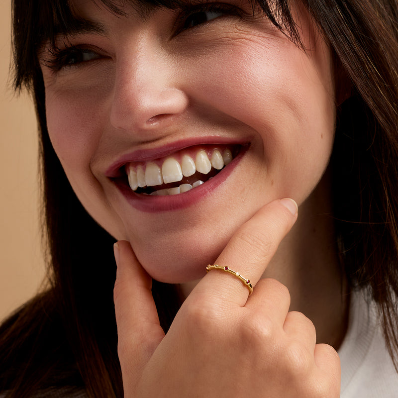 Ruby and diamond ring on finger in 14k yellow gold band with side stones