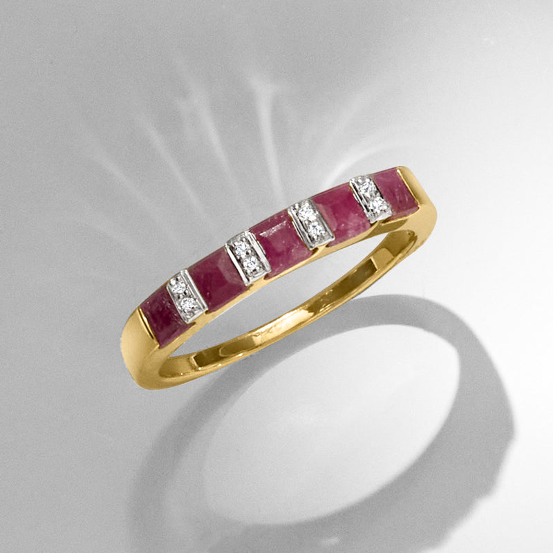 Gold row ring with square ruby stones and diamond accents, angled view