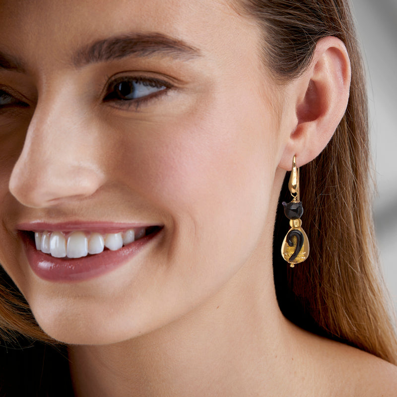 Cat drop earrings worn on ear: black glass cat bead with golden Murano details
