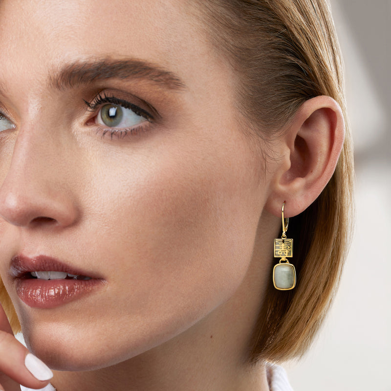 Green jade drop earrings in gold with leverback hoops, worn dangling at ear