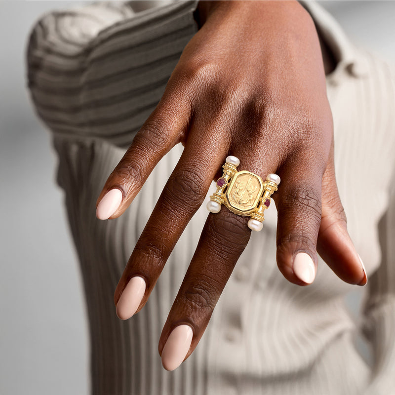 Gold-tone ring on hand with octagonal textured setting, pink ruby accents, white pearls