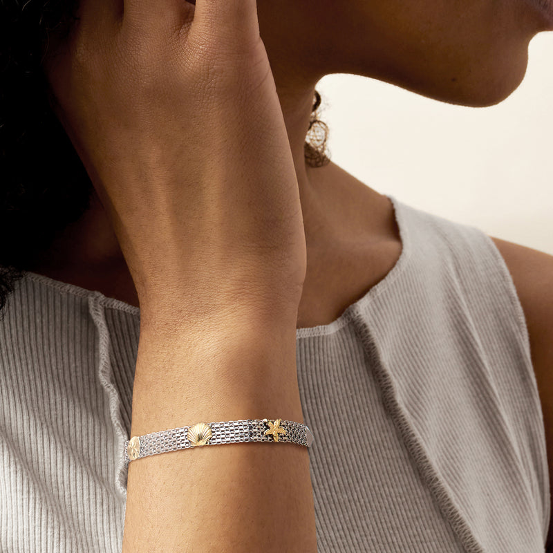Sterling silver bolo bracelet worn on wrist with woven chain and gold-tone shell detail