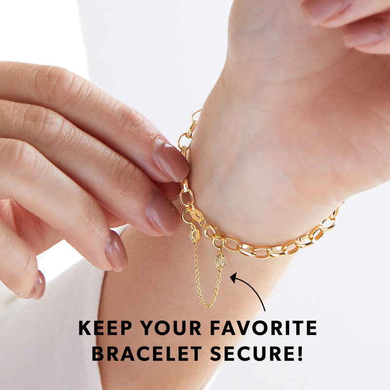 Gold safety chain with circular loop clasps clipped to a bracelet on wrist