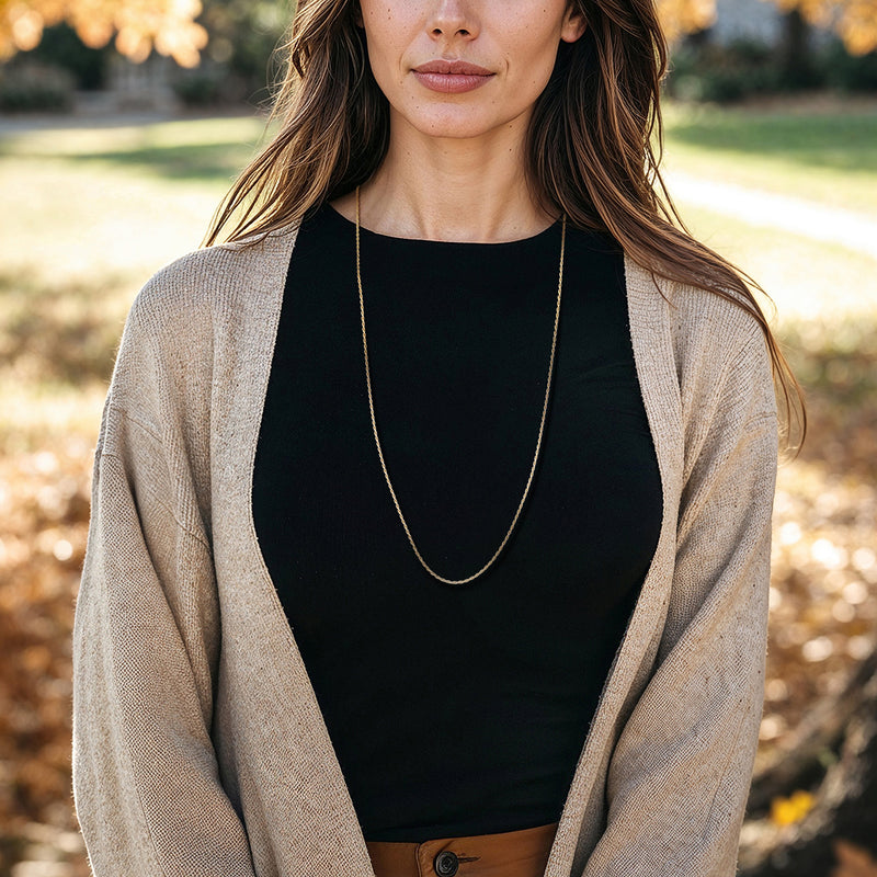 Gold rope-chain necklace hanging at the neckline on a cardigan
