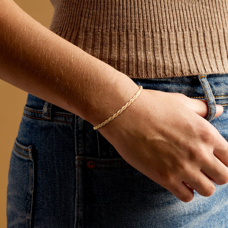 Gold rope-chain bracelet on wrist with twisted link pattern