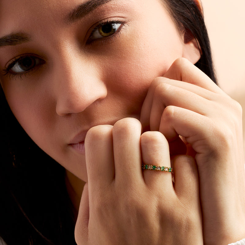 Emerald and diamond ring on finger, emerald-cut green stones in 14kt yellow gold band