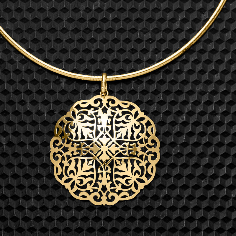 Close-up yellow gold filigree medallion pendant with detailed scrollwork