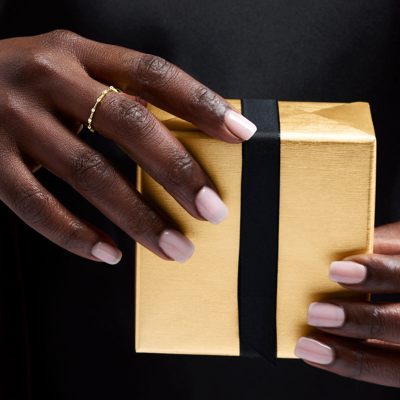 Yellow gold diamond station ring on finger, small round stones on a slim band