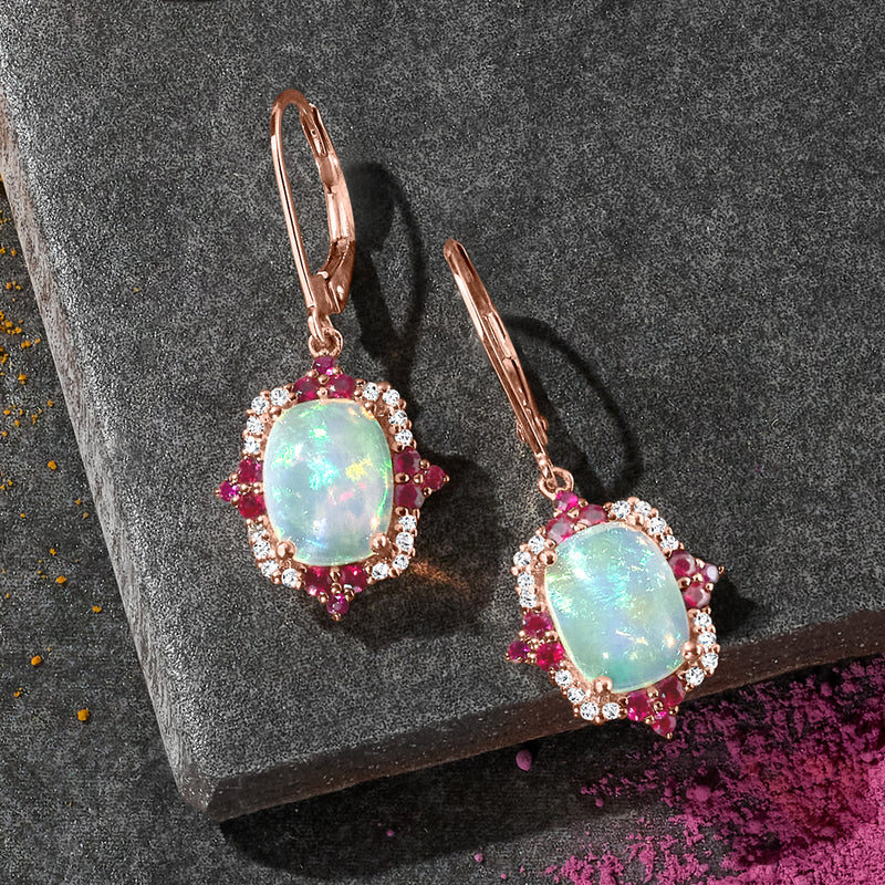 Rose gold leverback drop earrings with oval opal center, ruby clusters and diamond rim