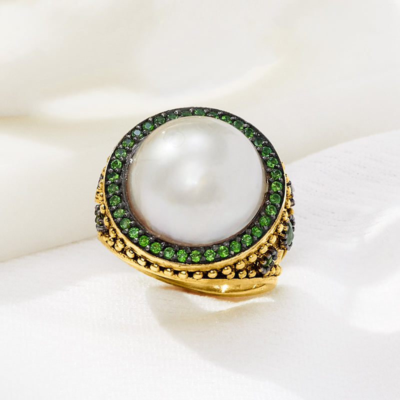 Gold mabe pearl ring with green gemstone border and round white center