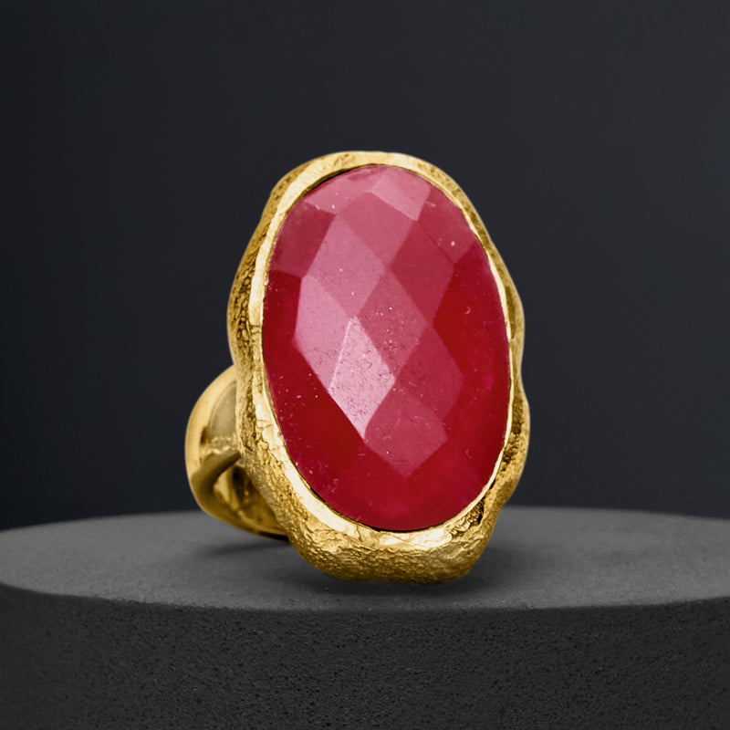 Gold-tone oval pink gemstone ring in angled view with sculpted gold bezel