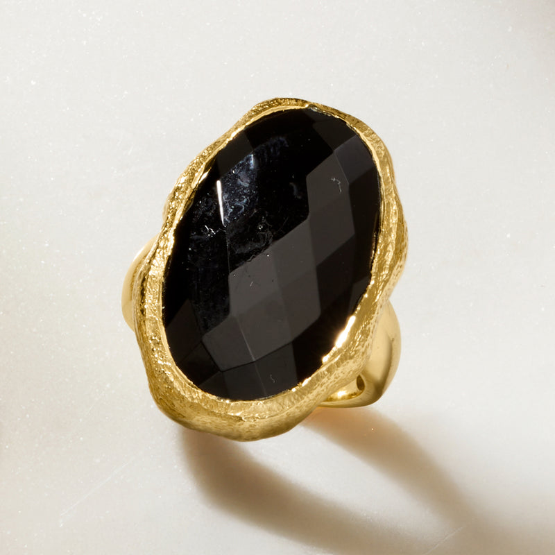 Gold-tone oval onyx ring featuring faceted black stone and split band