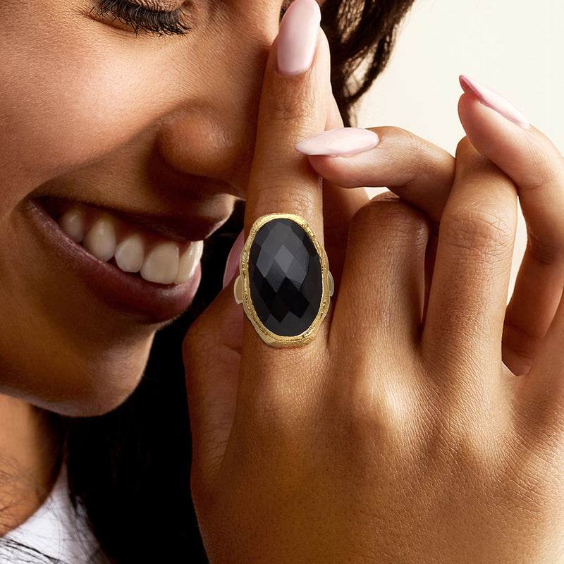 Oval onyx ring on finger with gold-tone setting and faceted black gemstone