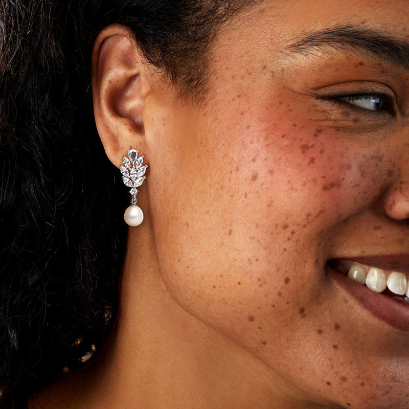 Sterling silver CZ and pearl drop earrings on ear, with dangling white cultured pearl
