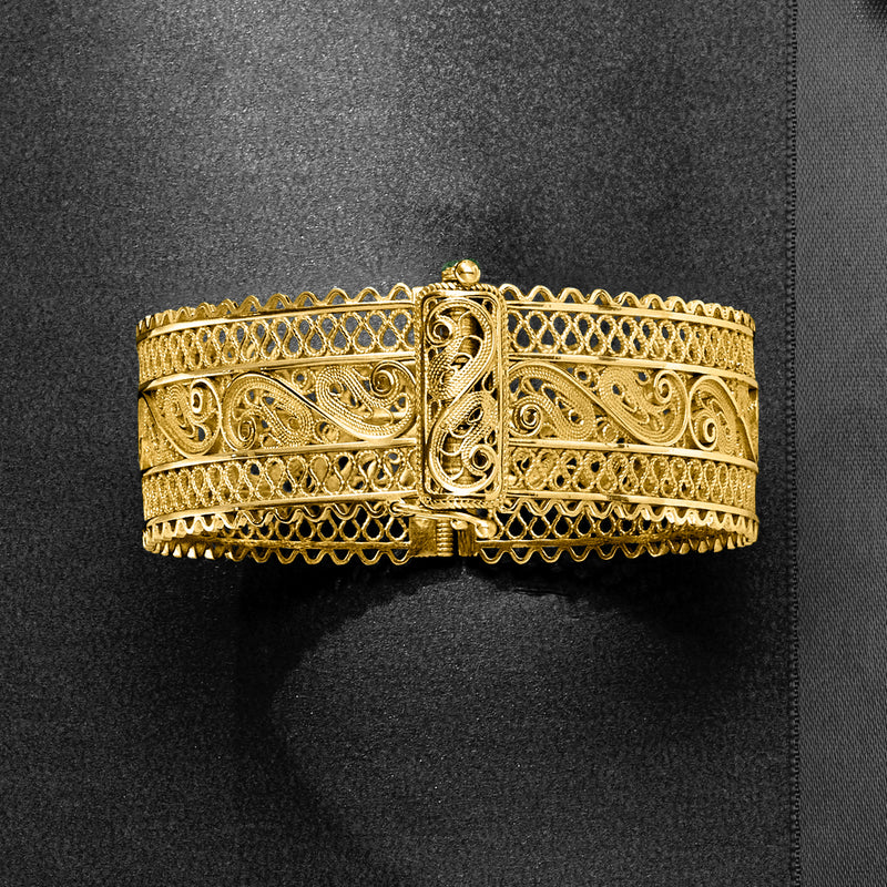Wide gold filigree bangle bracelet with textured lattice edge and detailed front clasp