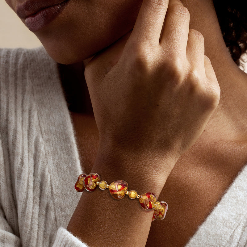 Heart charm bracelet on wrist with red and gold Murano glass heart beads