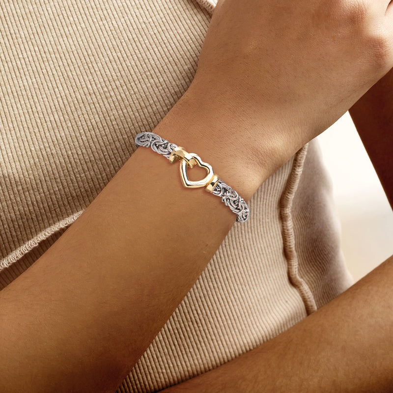 Two-tone silver heart bracelet on wrist, gold heart accent in woven chain
