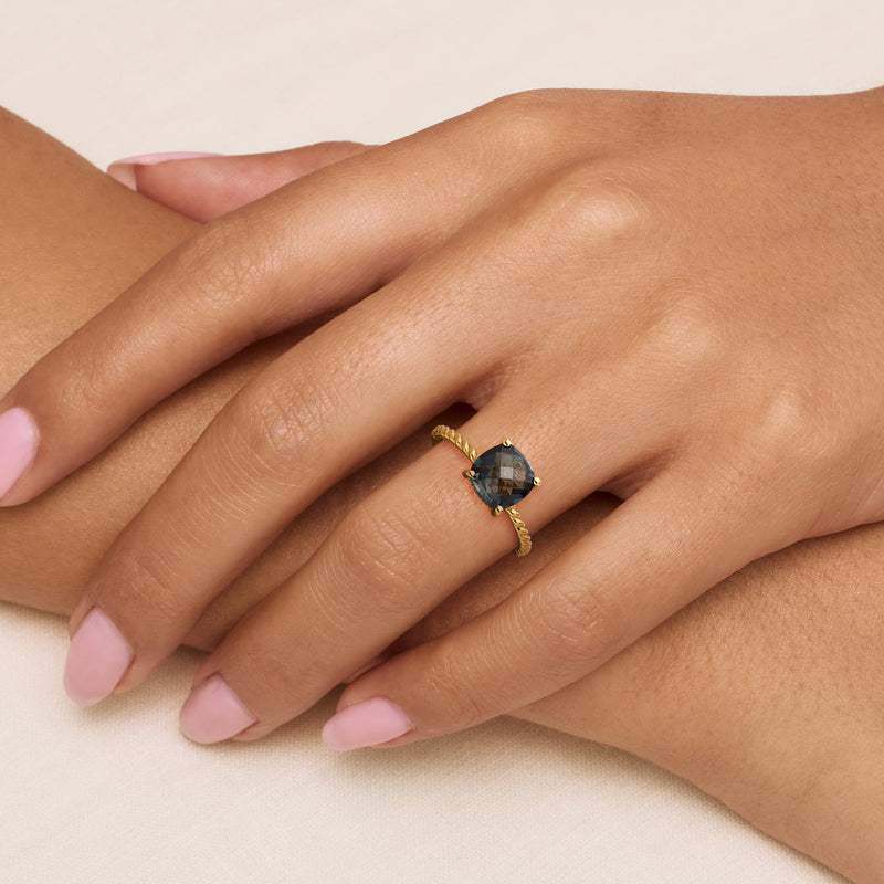 Gold-toned ring with dark blue round gemstone and small accent stones