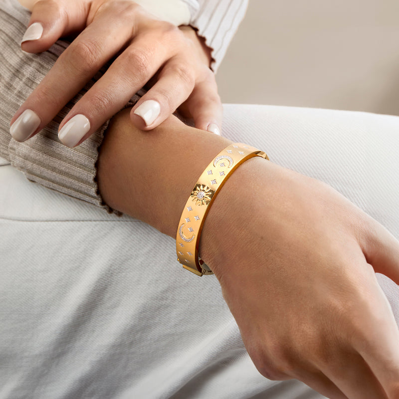 Celestial bangle bracelet on wrist with moon, sun, and star diamond accents
