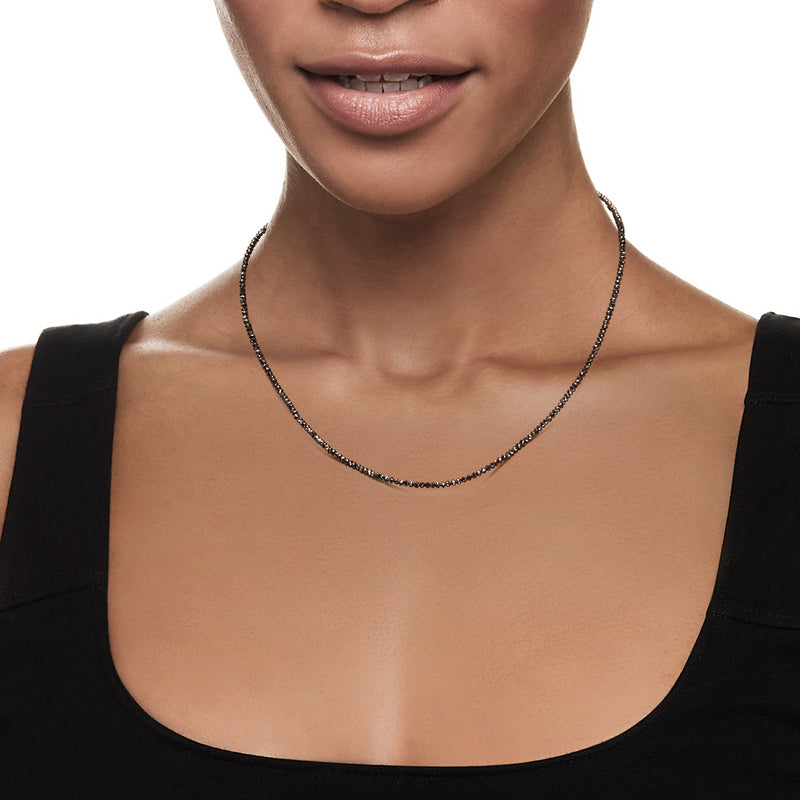 Black diamond bead necklace worn at the neckline with small dark round beads