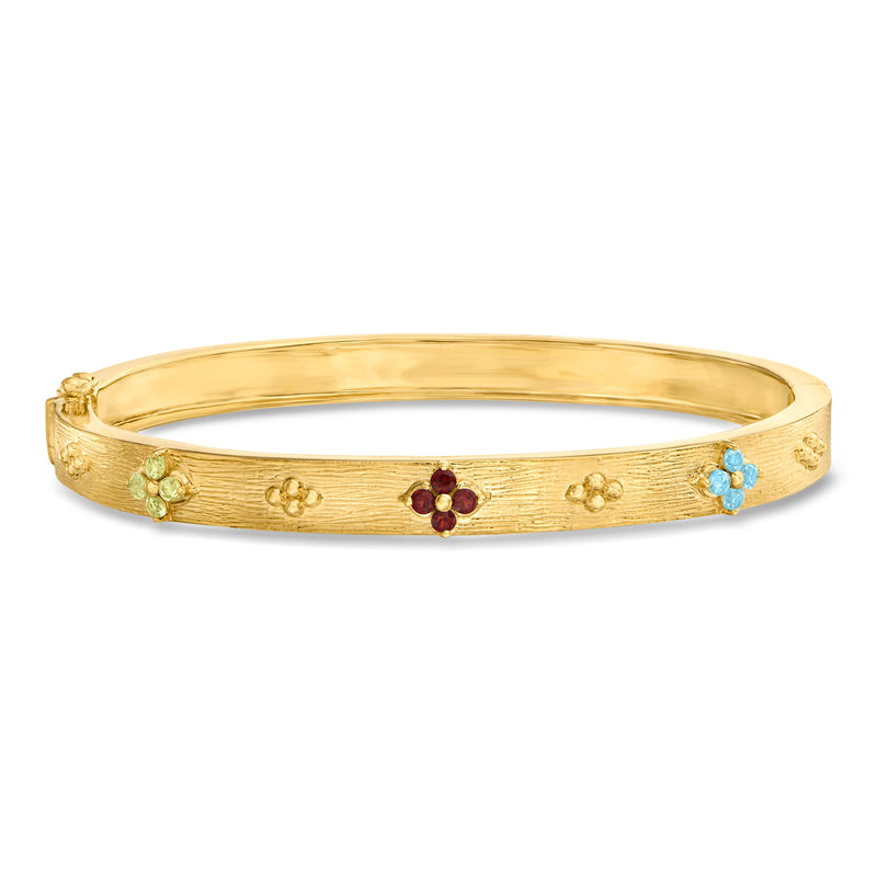 Gold bangle bracelet with floral motifs and red and blue gemstones, open circle