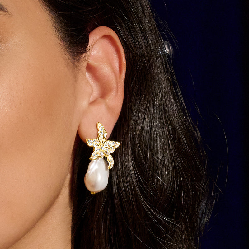 Gold CZ flower stud earrings with baroque pearl drop worn on ear