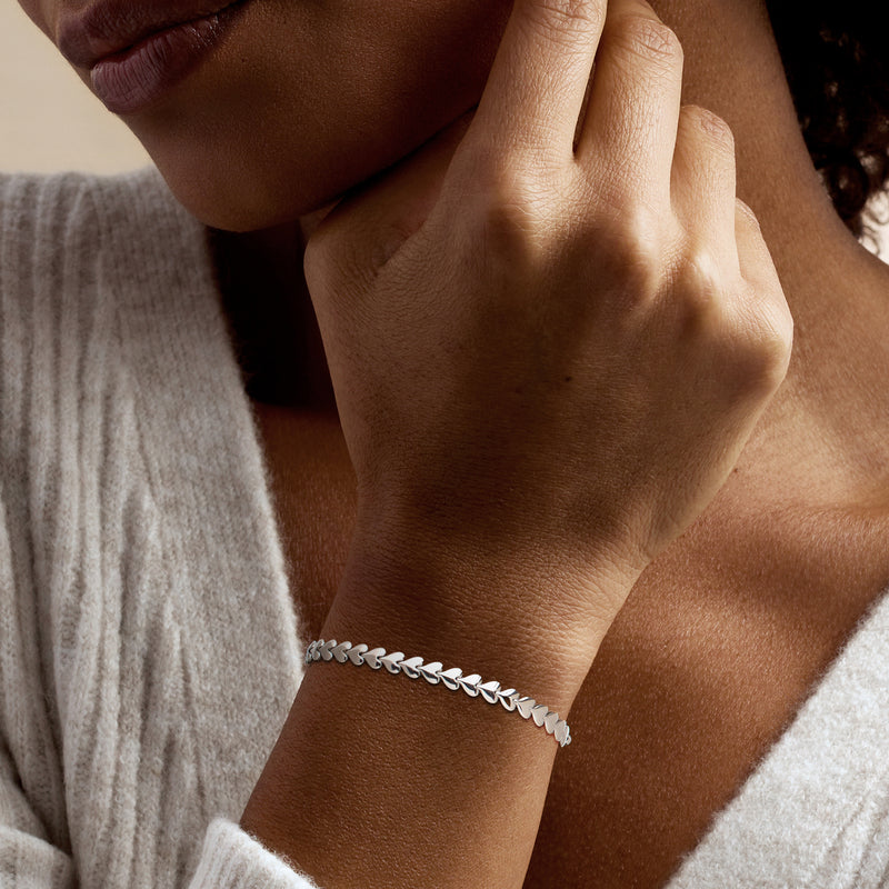 Sterling silver heart-link bolo bracelet on wrist with adjustable bolo cord and heart links