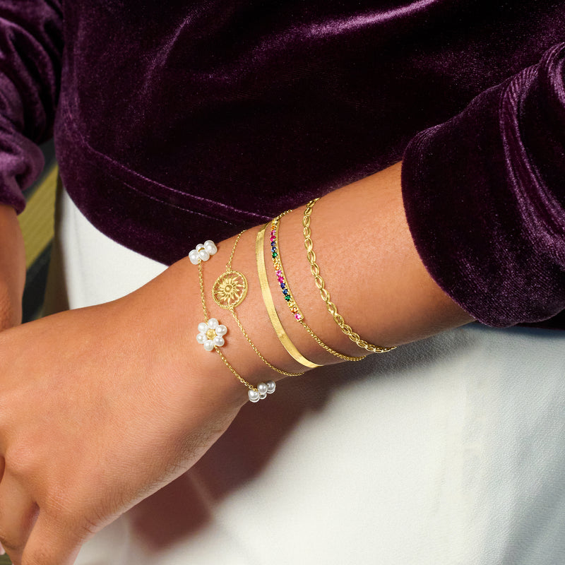 14kt yellow gold bracelet with pearl flower charms worn on arm with bangles