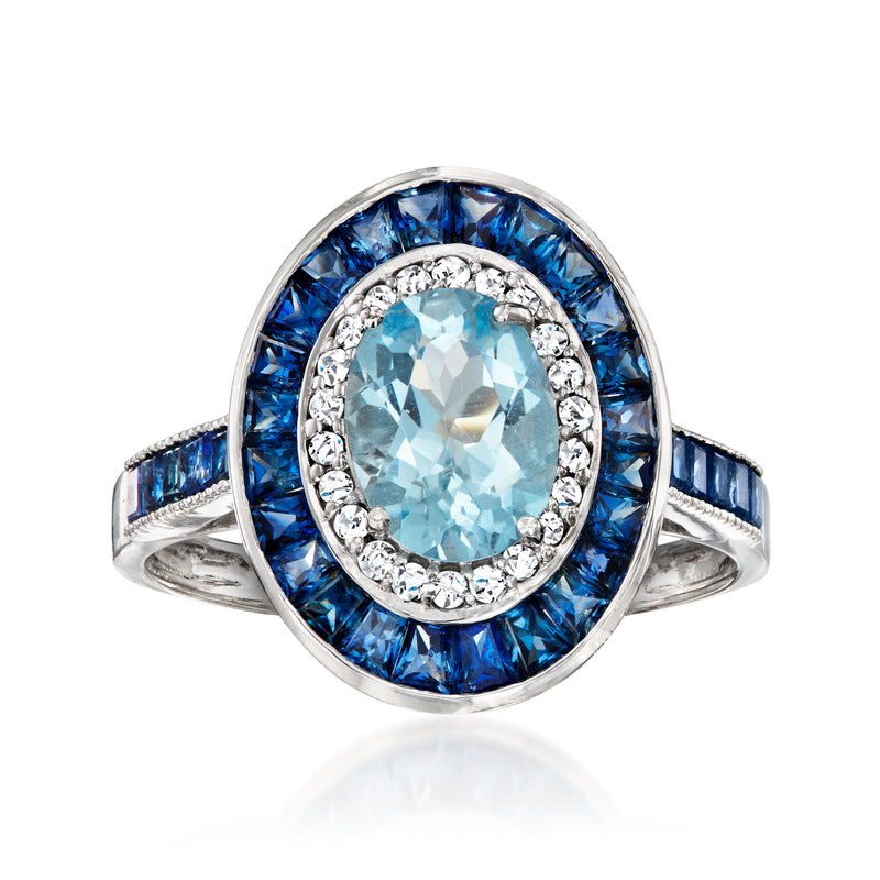Oval aquamarine center in diamond halo, surrounded by blue sapphire ring in 14kt white gold