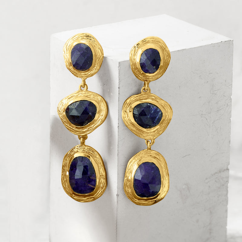 Gold drop earrings, side view, with three oval deep-blue sapphire stones