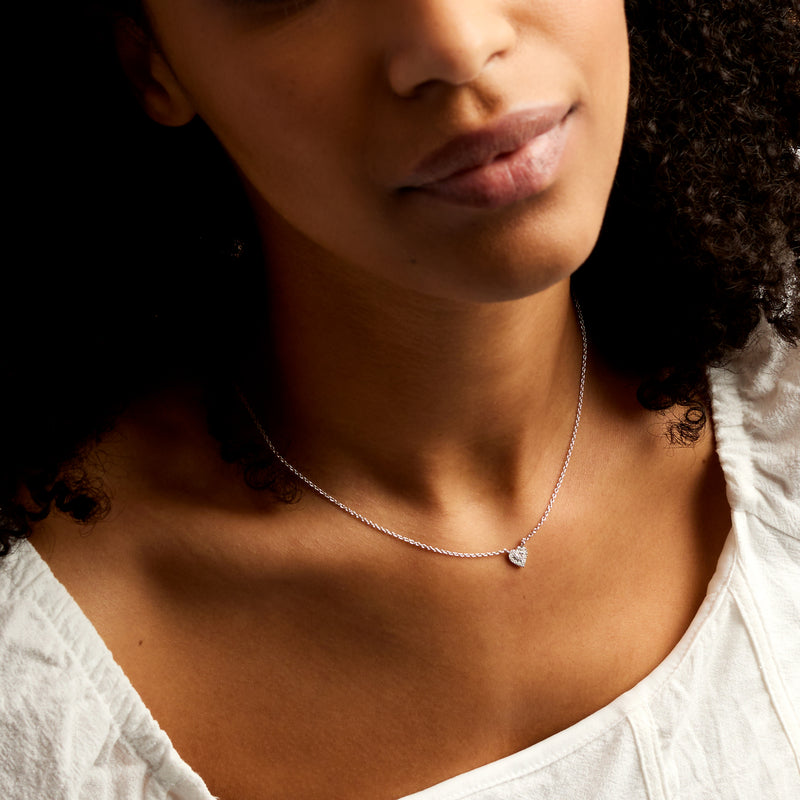 Sterling silver link chain necklace with small heart pendant, worn at collarbone
