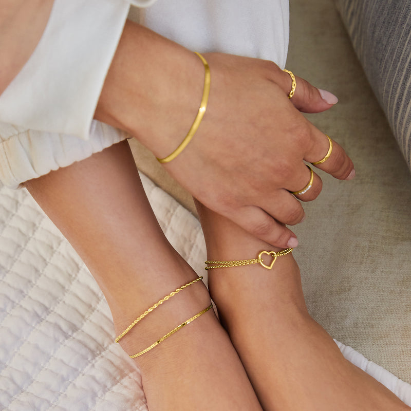 Yellow gold heart anklet worn on ankle, fine chain with small heart charm