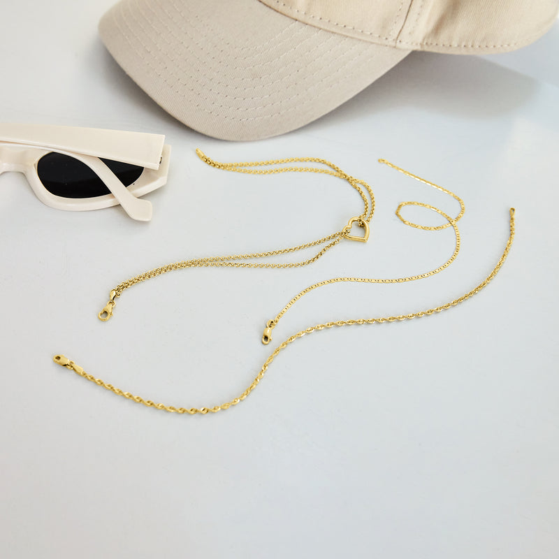 Yellow gold heart anklet laid flat, fine chain with heart station charm