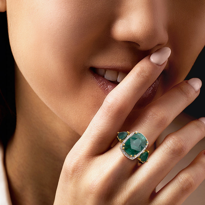 Green emerald and diamond halo ring on finger with 18kt gold setting